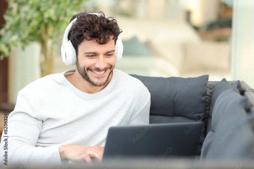 Happy man watching media on laptop in a house terrace Happy man watching media on laptop in a house terrace