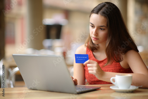 Serious woman buying online in a restaurant terrace