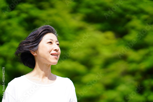 緑の中気持ちよさそうに髪を風になびかせる中年女性 © sakura