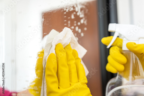 close-up woman's hand in a glove with a spray washes and cleans the glass in the wardrobe