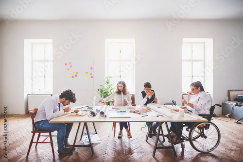 Young group of colleagues working on a new project together in a startup company office. Working in co-working space.