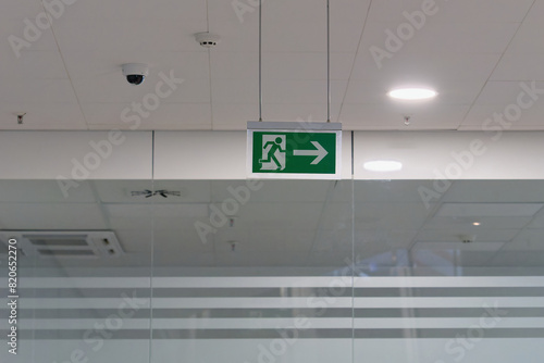 Escape route (emergency exit) sign on the ceiling of the modern building