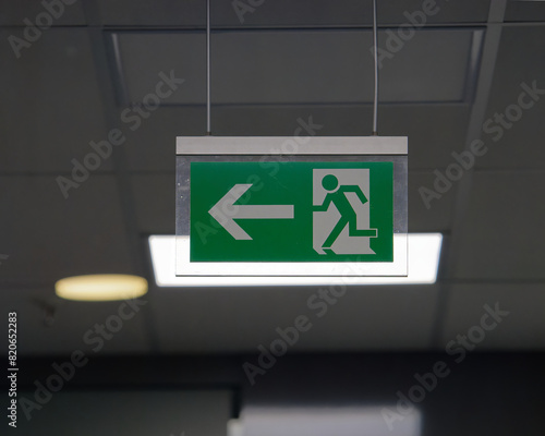 Selective focus photo of an escape route (emergency exit) sign on the ceiling of the building 