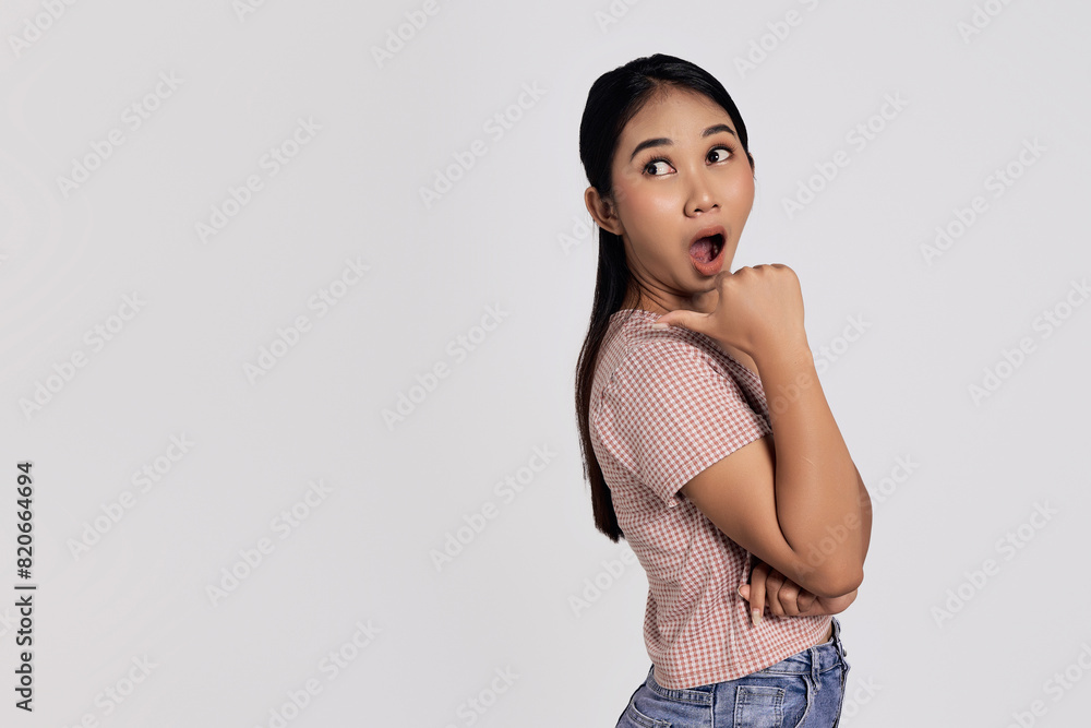 Shocked impressed young Asian woman wearing casual clothes pointing finger aside isolated on white background. People lifestyle concept Shocked impressed young Asian woman wearing casual clothes pointing finger aside isolated on white background. People lifestyle concept