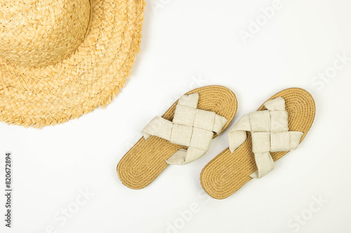Top view of straw hat and slippers on white background. Summer fashion, vacation and beach wallpaper. Copy space, flat lay.