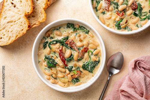 Bowls with Tuscan butter beans stew with spinach and sun-dried tomato, vegan cream. Vegetarian homemade meal.