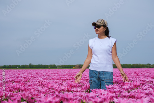 Wallpaper Mural A graceful woman standing amidst a vibrant field of pink tulips in Texel, Netherlands, as the colorful flowers sway with the gentle breeze. Torontodigital.ca