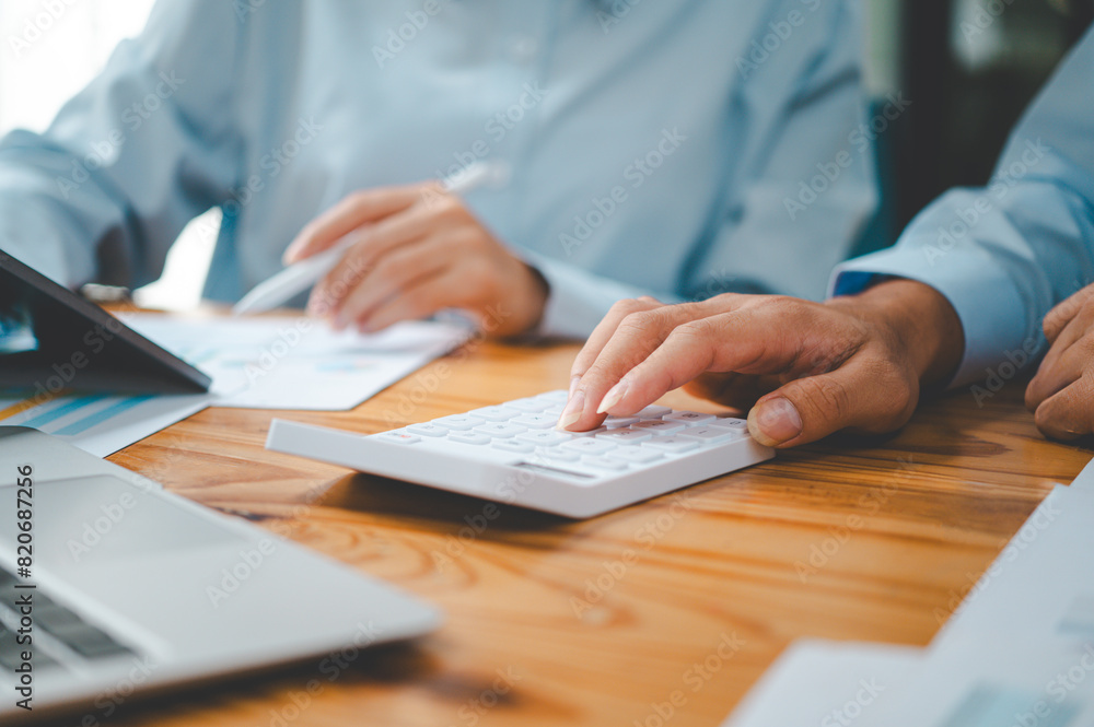 close up The business person is sitting on a calculator with a graph in the office of finance accounting concept close up The business person is sitting on a calculator with a graph in the office of finance accounting concept