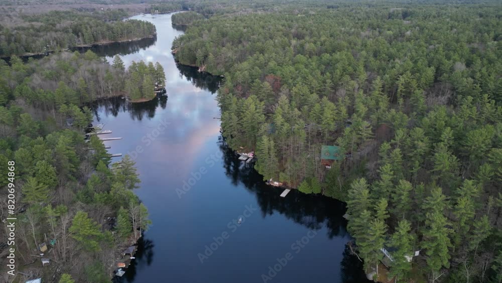 Aerial view of a person canoeing on a calm river winding through a dense forest, surrounded by lush greenery and natural beauty. Aerial view of a person canoeing on a calm river winding through a dense forest, surrounded by lush greenery and natural beauty.