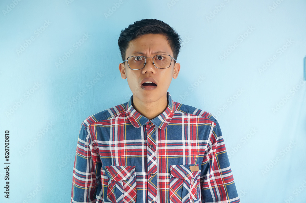 Surprised expression of young asian man wearing glasses and red shirt Surprised expression of young asian man wearing glasses and red shirt