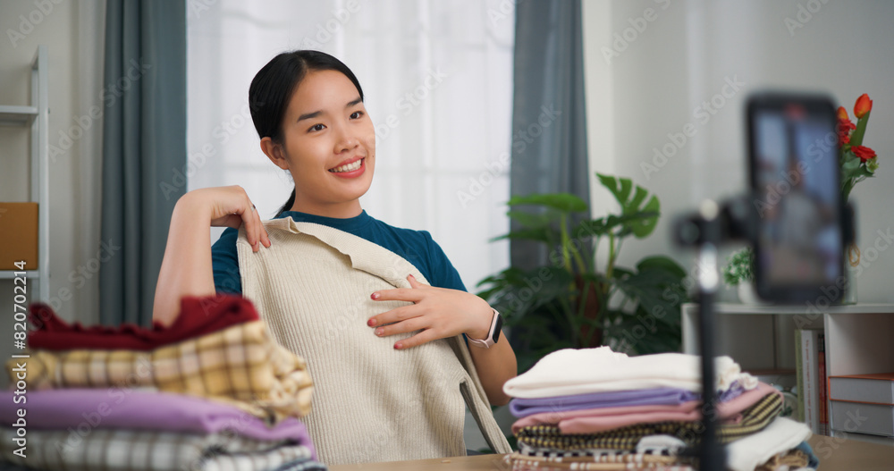 Portrait of Young asian woman business owner selling clothes live streaming on mobile phone show new collection fashion clothes to customer ,Online Shopping
