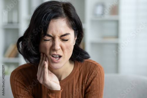 Fotografie Woman experiencing severe toothache at home, displaying pain and discomfort