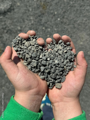 Kinderhände die Kies Steine halten in Form eines Herzens