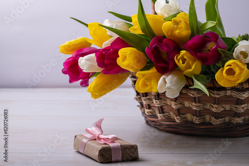 A close-up of a basket with colorful blooming tulips. Holiday card. Copyspace.