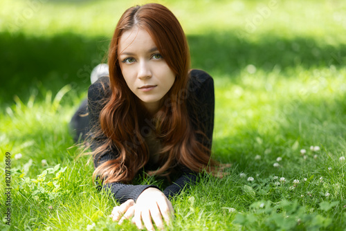 Beautiful girl with red hair enjoying summertime in the park.