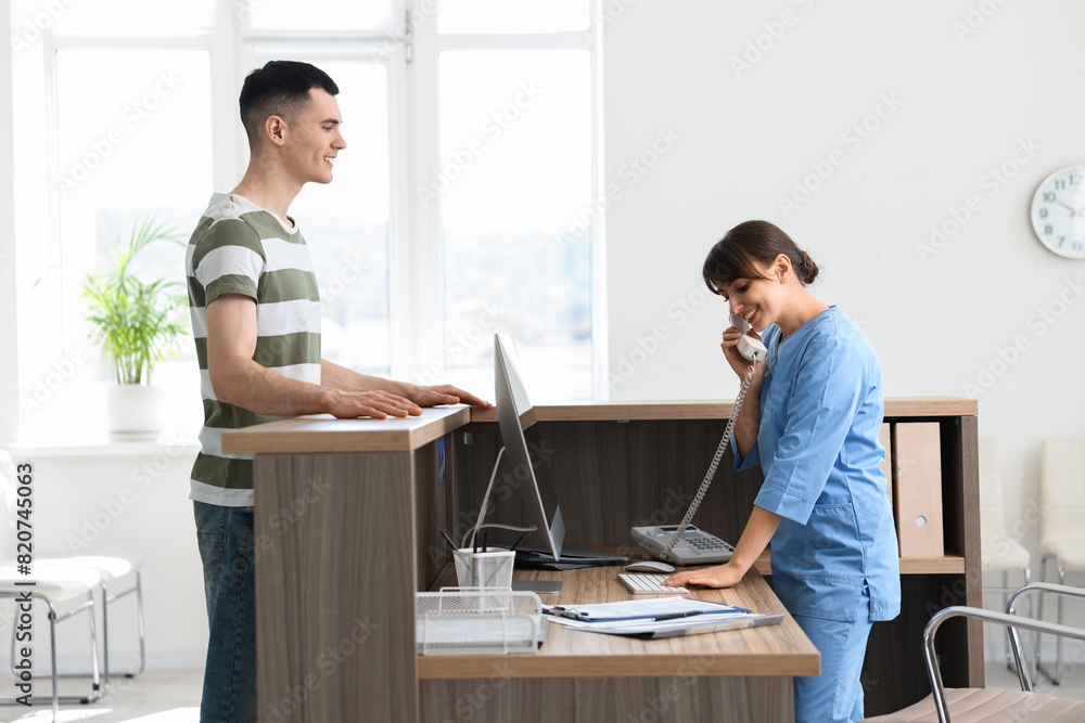 Smiling medical assistant working with patient at hospital reception Smiling medical assistant working with patient at hospital reception