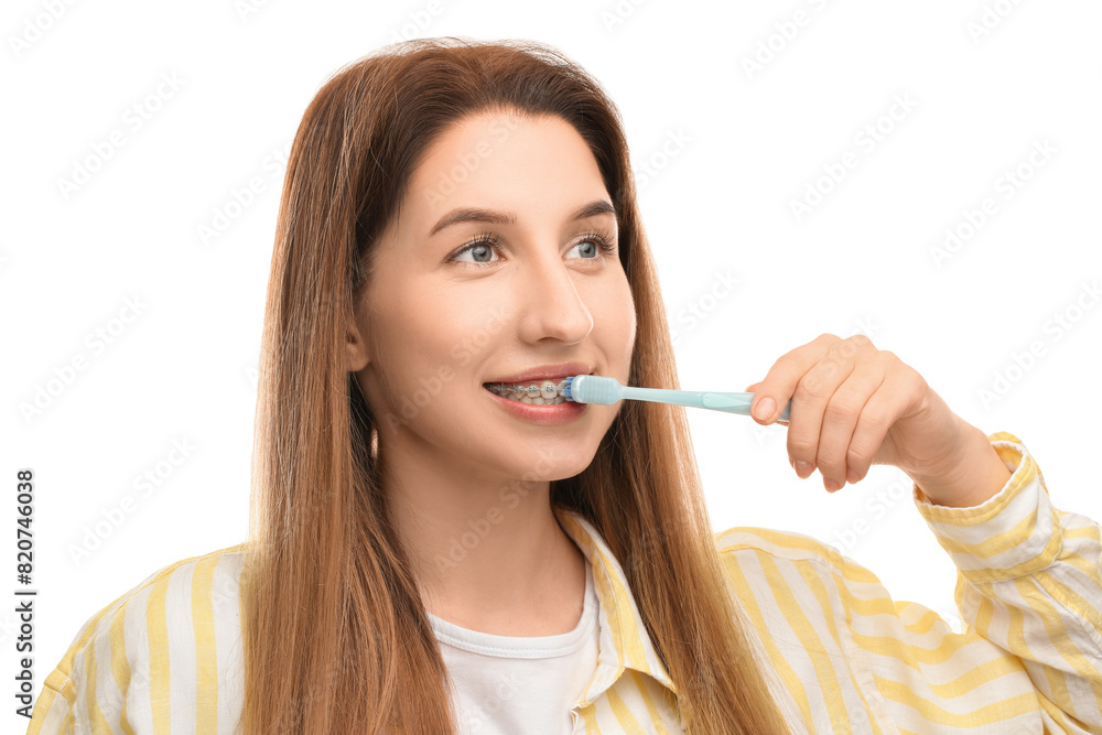 Smiling woman with dental braces cleaning teeth on white background Smiling woman with dental braces cleaning teeth on white background