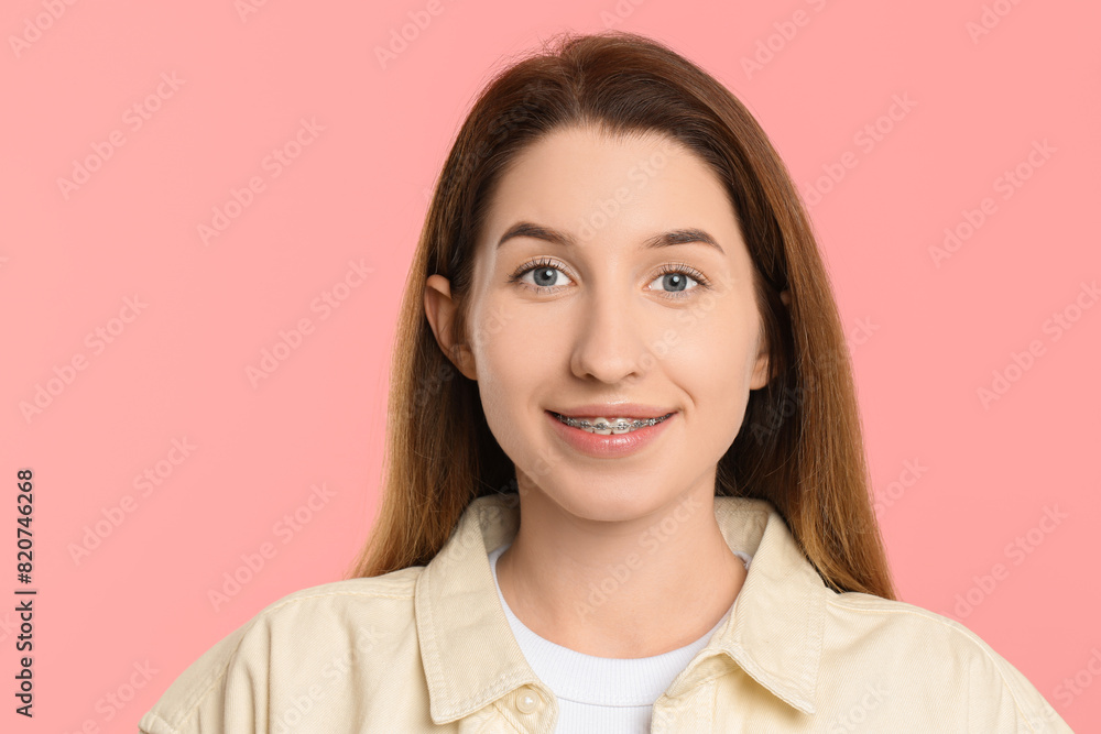 Portrait of smiling woman with dental braces on pink background