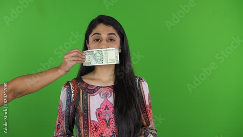 A portrait shot of an Indian woman stopped speaking due to the cash note on her mouth - money power  corruption. A Young journalist getting bribed not  to speak ill against any political party - Me... photo
