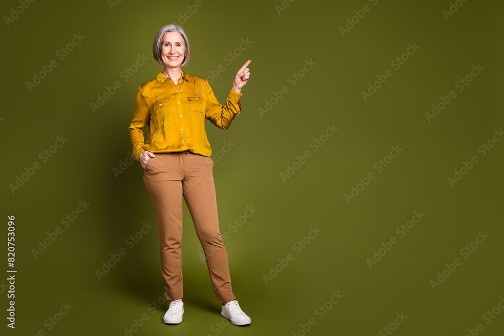 Full length photo of charming positive woman wear shirt smiling showing empty space isolated khaki color background Full length photo of charming positive woman wear shirt smiling showing empty space isolated khaki color background