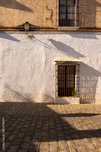 Warm sunlight casts striking shadows on a textured Spanish wall in a historic street of Carmona, Andalusia, Spain photo