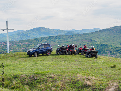 A group of friends riding quad bikes, admiring the landscape from the top of the hill.