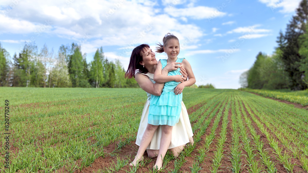 Happy mother and daughter enjoying rest, playing and fun on nature in green field. Woman and girl resting outdoors in summer and spring day Happy mother and daughter enjoying rest, playing and fun on nature in green field. Woman and girl resting outdoors in summer and spring day