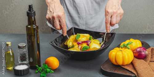 A woman is preparing a tomato salad. Ripe vegetables, herbs, aromatic spices, olive oil