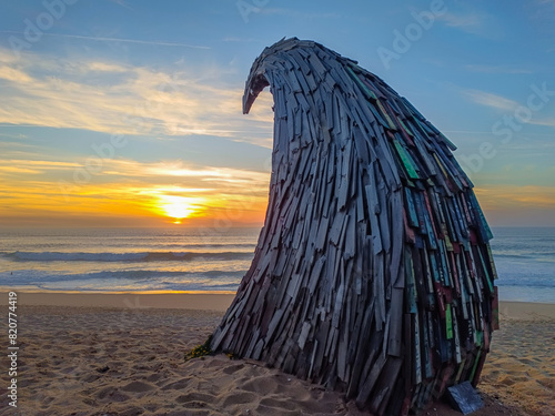 Wave of pieces of wood framing the sunset on the horizon reflected in the sea at Física beach, Santa Cruz - Torres Vedras PORTUGAL