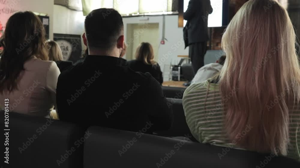 A man and two women are sitting at a conference and listening to a man speaking on stage. View from the back. Unrecognizable faces. High quality 4k footage A man and two women are sitting at a conference and listening to a man speaking on stage. View from the back. Unrecognizable faces. High quality 4k footage