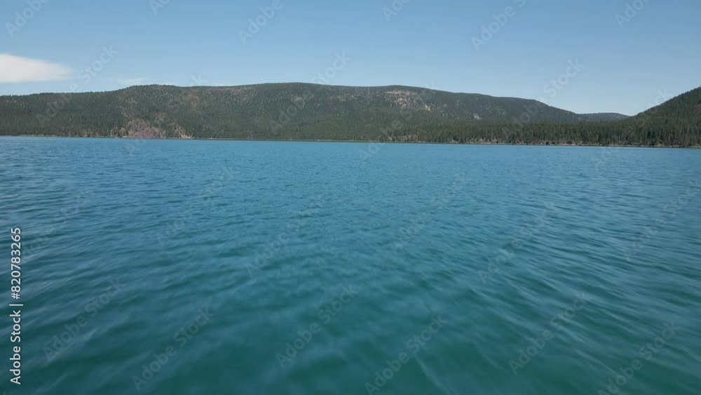 Drone flying fast over the sea surface with green hills on the horizon Drone flying fast over the sea surface with green hills on the horizon