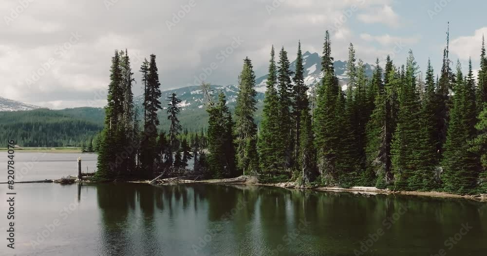 Landscape scene of pine trees by Sparks Lake with snowy mountains range on the horizon Landscape scene of pine trees by Sparks Lake with snowy mountains range on the horizon