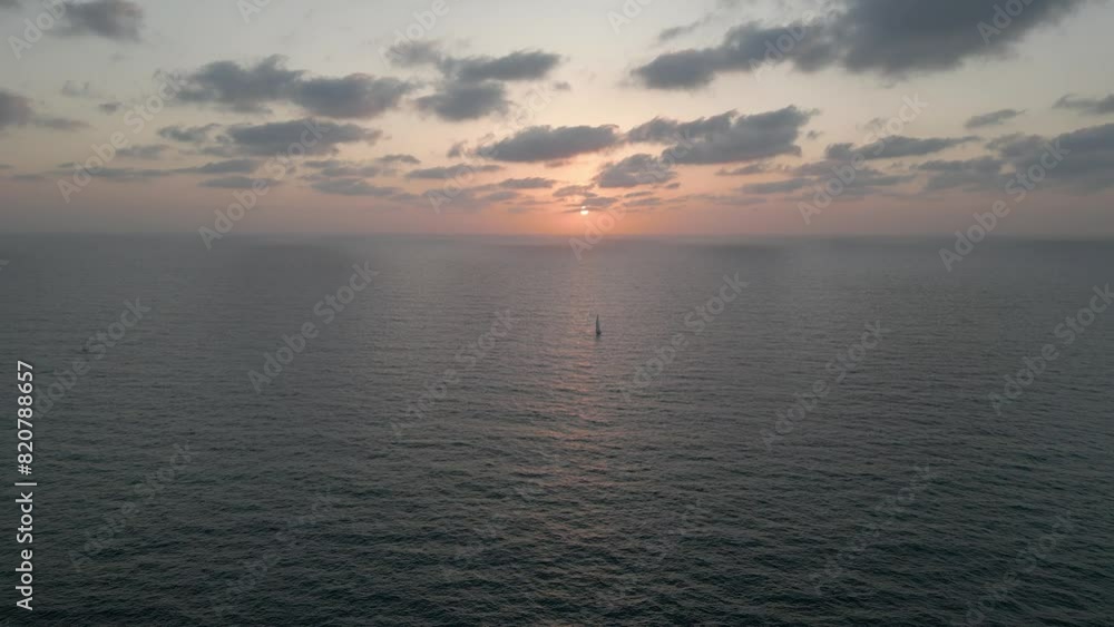 Calm scene of gray sky with a boat in a distance with orange cloudy sunset sky on the horizon Calm scene of gray sky with a boat in a distance with orange cloudy sunset sky on the horizon