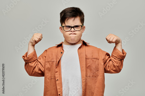 Konstfotografi A little boy with Down syndrome with glasses flexes his muscles, showcasing his strength and determination