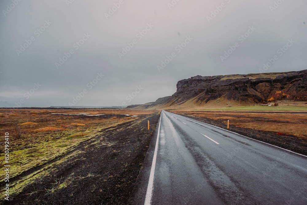 Fototapeta premium a narrow empty road in a mountainous area, with a grey sky above