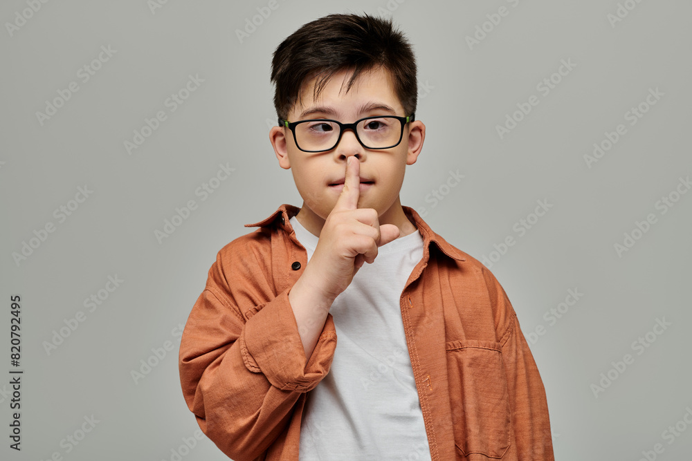 little boy with Down syndrome with glasses making a hush sign. little boy with Down syndrome with glasses making a hush sign.