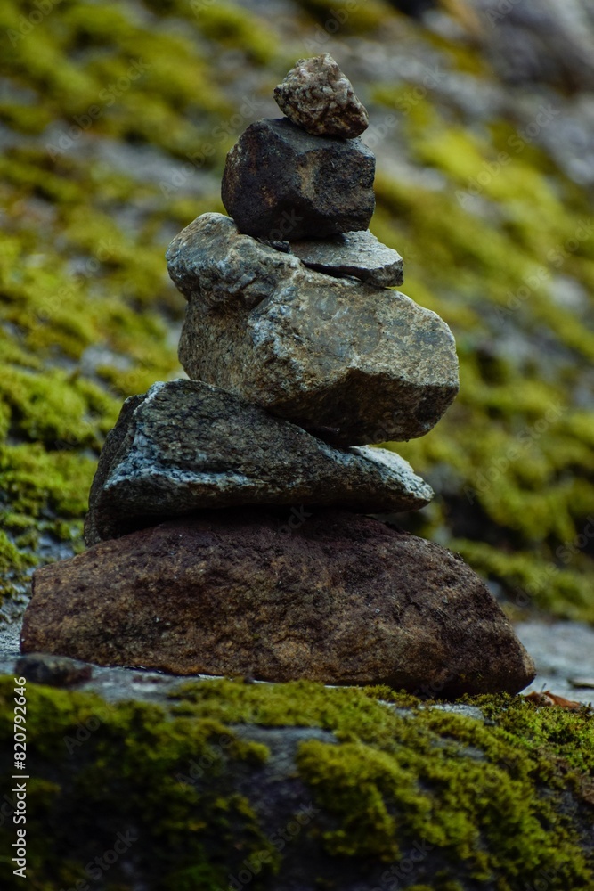 Vertical shot of stacked rocks on a lush green mossy surface Vertical shot of stacked rocks on a lush green mossy surface