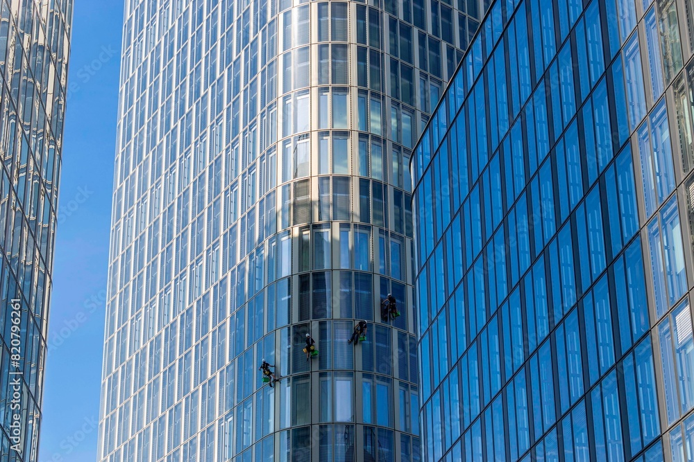 Low angle shot of window cleaners working on skyscrapers in the daylight Low angle shot of window cleaners working on skyscrapers in the daylight