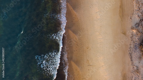 Golden hour aerial: Sandy beach, gently rolling waves in Sopot, Poland. © Grzegorz