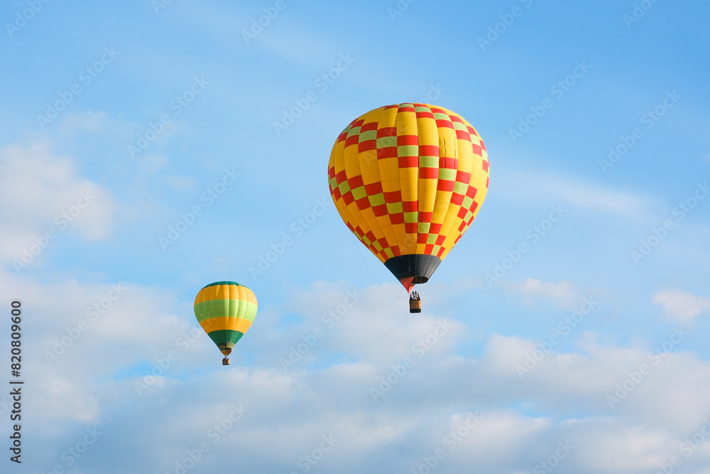 Two hot air balloons with tourists against a blue sky. Beautiful view of colourful hot air balloons from below Two hot air balloons with tourists against a blue sky. Beautiful view of colourful hot air balloons from below