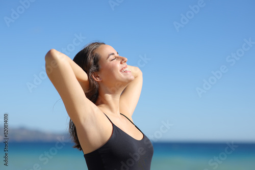 Happy woman showing waxed armpit breathing on the beach