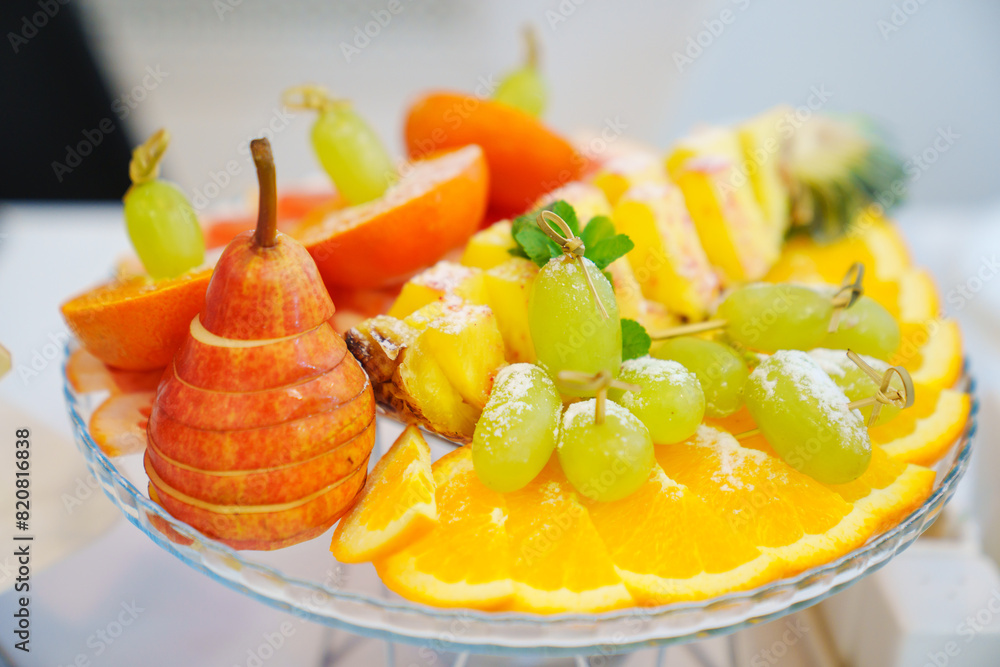 Fruit platter with powdered sugar for the banquet table. Assorted pears, grapes, oranges, pineapples and peaches. Fruit platter with powdered sugar for the banquet table. Assorted pears, grapes, oranges, pineapples and peaches.