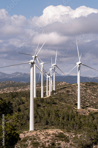 Line of wind turbines on a remote hill, generating renewable energy under a vast cloudy sky in Catalonia in Spain photo
