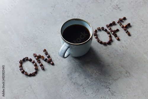 The image depicts the words "on" and "off" arranged with coffee beans, with a cup of freshly brewed black coffee in between. © Grzegorz