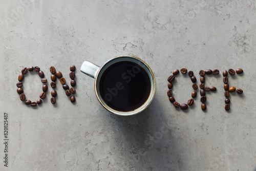 The image depicts the words "on" and "off" arranged with coffee beans, with a cup of freshly brewed black coffee in between.  © Grzegorz