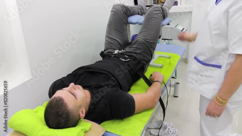 Footage of a patient lying on his back at the back stretching therapy at a physiotherapist