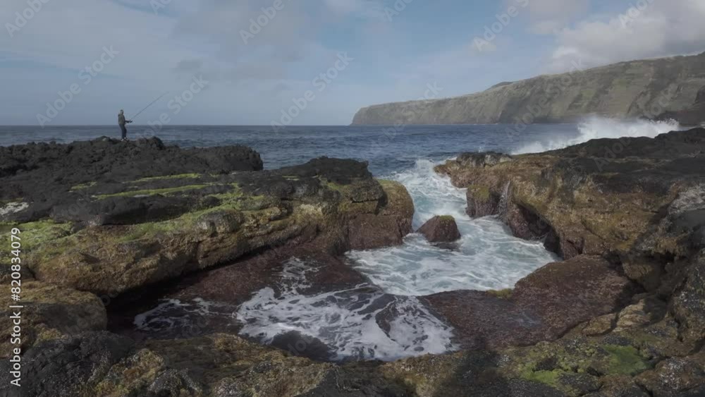 Lone person standing on rugged volcanic rocks by the ocean in Mosteiros, Sao Miguel, wide shot Lone person standing on rugged volcanic rocks by the ocean in Mosteiros, Sao Miguel, wide shot