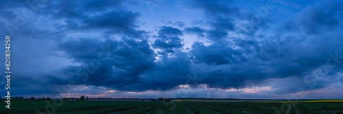 A wide majestic view of a panoramic dark sunset over the fields.	
