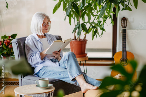 Принти на полотні Beautiful mature woman reading book, feeling cozy and happy
