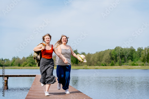 Two women running happily on a dock, holding hands and smiling outdoors